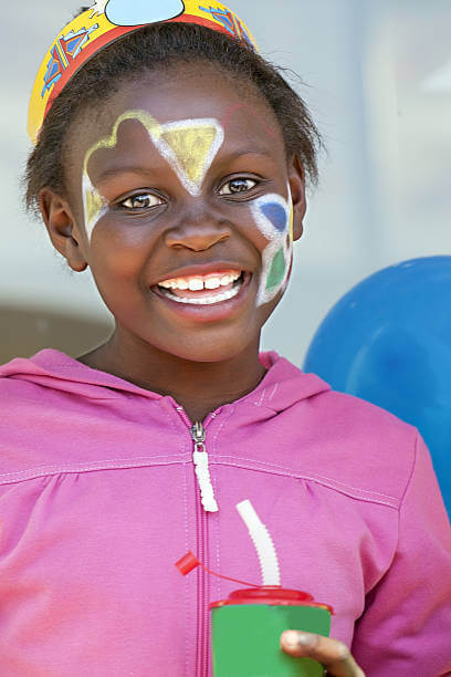 African girl holding a coldrink with face paint and a big smile at the birthday party